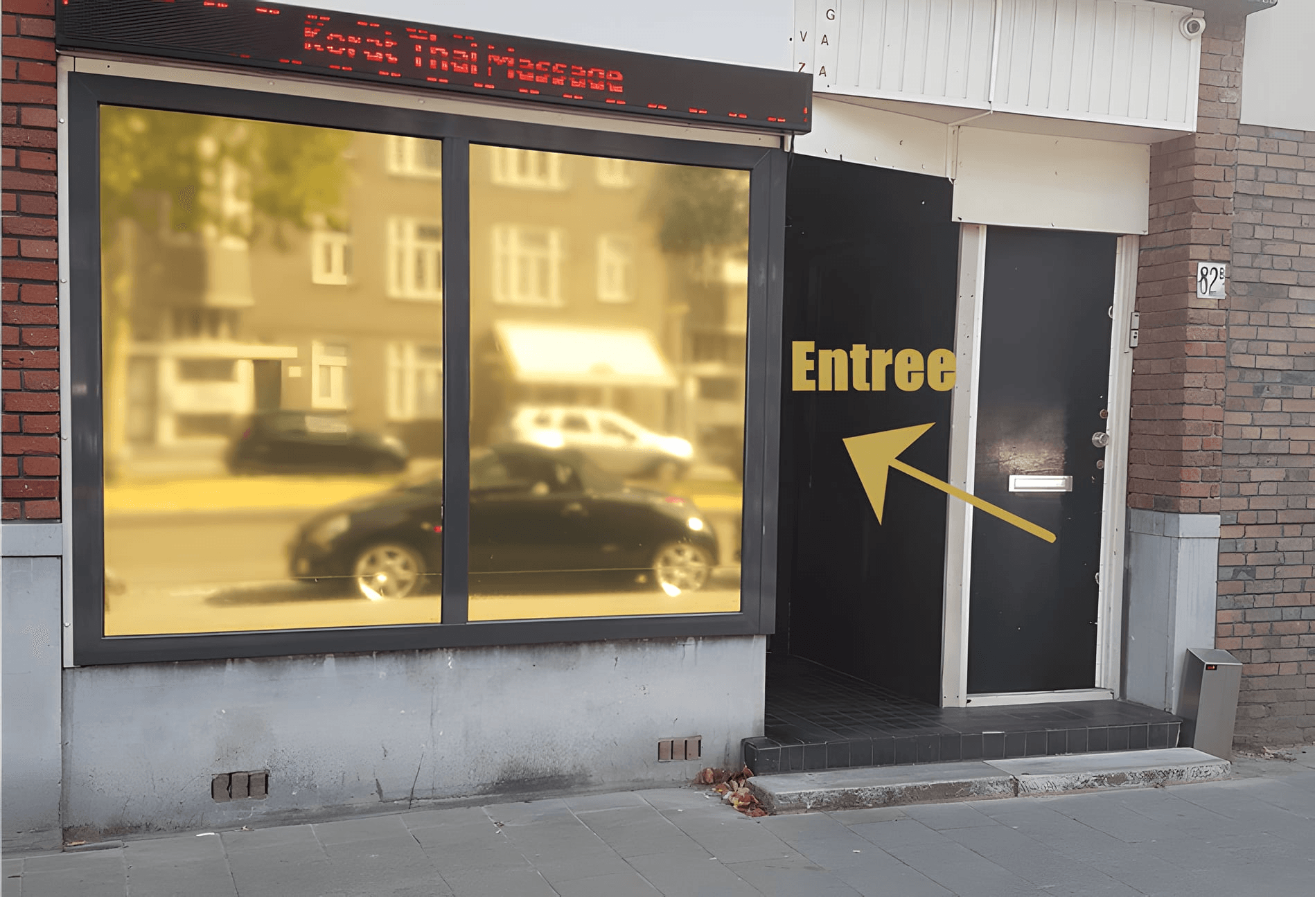 De gevel van Korat Thai Massage aan de Strevelsweg met gouden ramen en de zwarte deur met het bord Entree